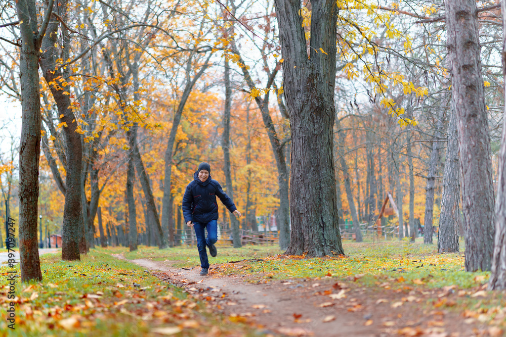 a boy running through the park and enjoys autumn, beautiful nature with yellow leaves a boy running through the park and enjoys autumn, beautiful nature with yellow leaves