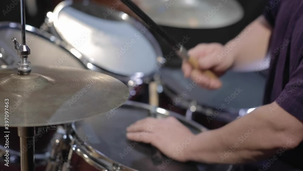Man playing drums with brushes in studio space Man playing drums with brushes in studio space