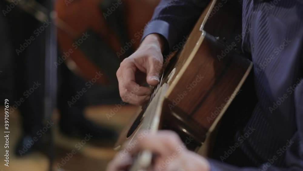 Man playing acoustic guitar with band in background Man playing acoustic guitar with band in background