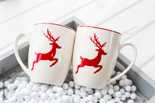 Two white coffee cups with a Christmas deer pattern. Beautiful holiday glass cups