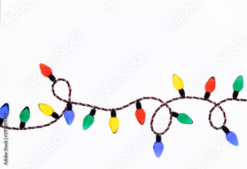 Original Christmas photograph of a string of bright red, green, yellow and blue Christmas lights looped across a bright white background.