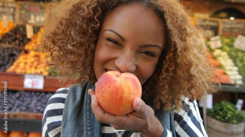 Woman eating peach from fruit stand, New York City, New York, United States photo