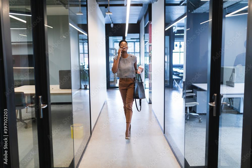 © Wavebreak Media - Smiling african american woman walking talking on smartphone in office © Wavebreak Media - Smiling african american woman walking talking on smartphone in office