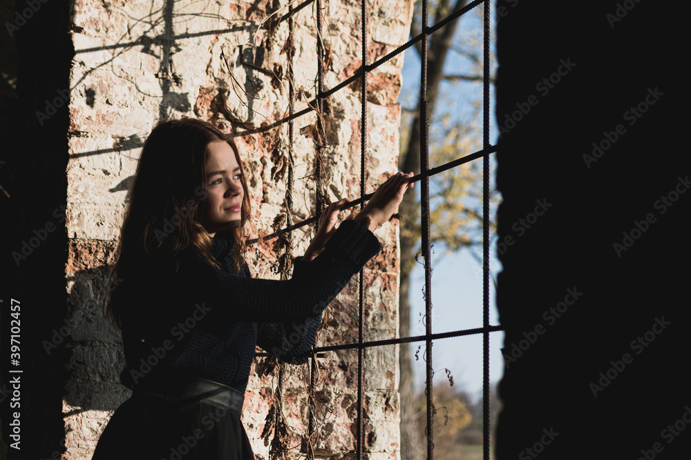 A young girl looks out of an old window in an ancient fortress