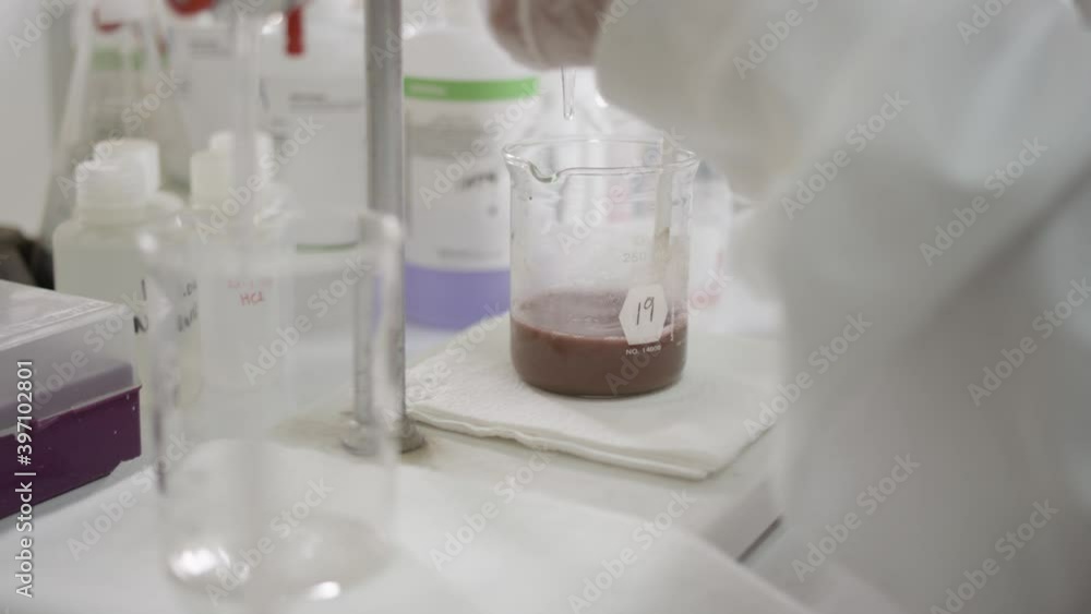 Scientist stirring solution in beaker in a real lab Scientist stirring solution in beaker in a real lab