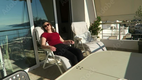 Young attractive woman enjoying the warmth of the sun on her balcony. Self care concept.