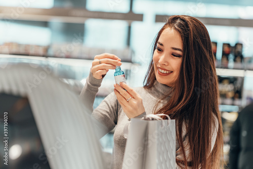 beautiful smiling Asian girl chooses and buys face serum cosmetics in the store. shopping