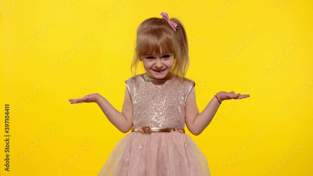 Irritated child girl in dress raising hands in questioning gesture why, what. Kid scolding with indignant expression, blaming in defeat. Yellow background studio. People emotions concept. Copy space Irritated child girl in dress raising hands in questioning gesture why, what. Kid scolding with indignant expression, blaming in defeat. Yellow background studio. People emotions concept. Copy space