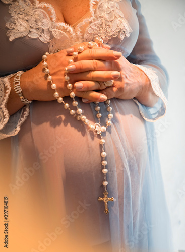 pregnant woman with rosary in blue dress