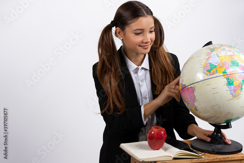 Girl holding globe, looks at it near book, apple. White background with space. photo