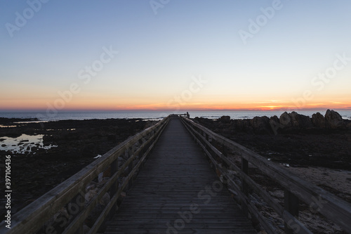 Praia do Coral sunset Viana do Castelo Portugal shore coast beach rocks sand footbridge pathway wooden blue violet sky