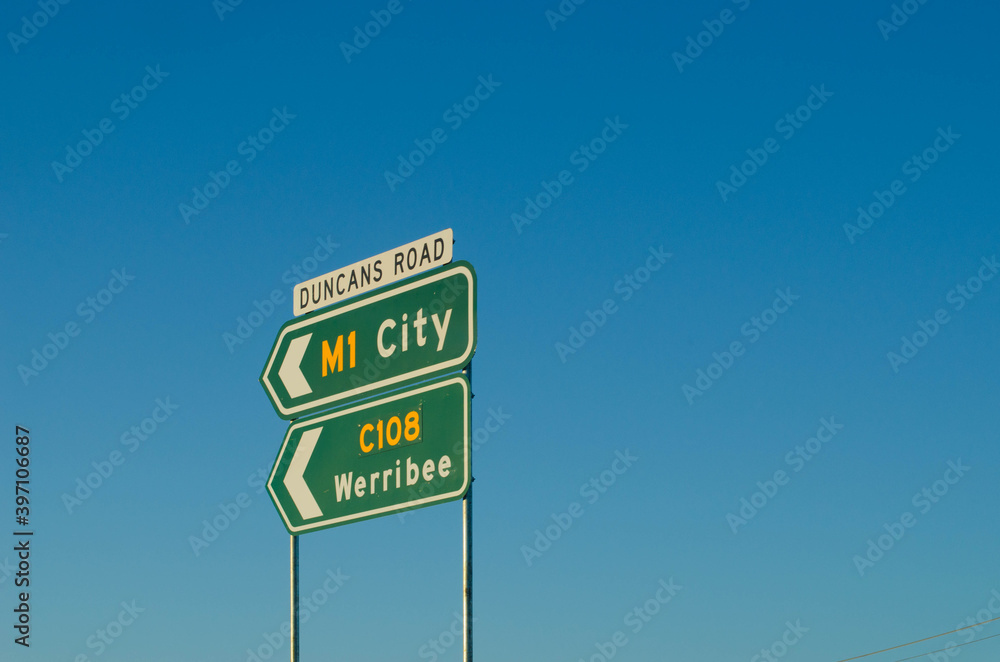 The road signs of M1 Princes Freeway to city and road c108 to Werribee against the blue sky. Melbourne, VIC Australia. Copy space for text. The road signs of M1 Princes Freeway to city and road c108 to Werribee against the blue sky. Melbourne, VIC Australia. Copy space for text.