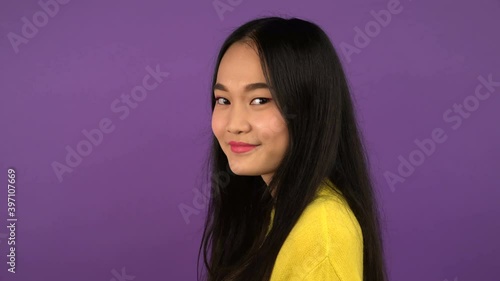 profile portrait of a young woman. the young woman slowly turns her head and smiles. Asian woman on purple isolated background. 4K