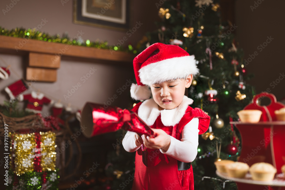 young girl playing chrismtas cracker in front of Christmas tree
