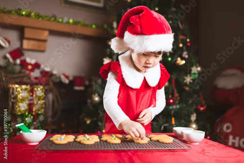 young girl decorating gingerbread man for celebrating  Christmas party © M-image