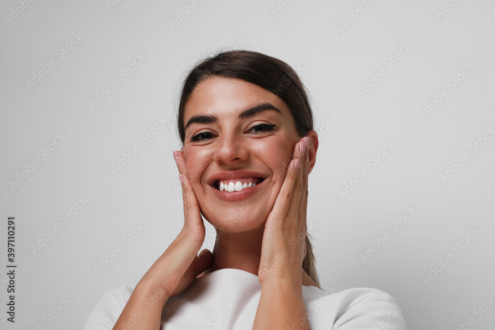 Close-up of a smiling young woman isolated over gray background. Close-up of a smiling young woman isolated over gray background.