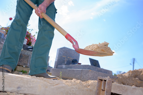 portrait of a worker digging a grave photo