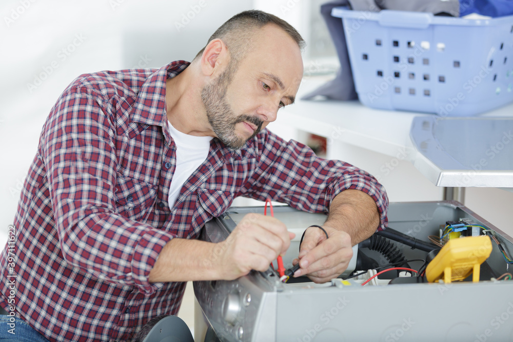 male technician inspecting and fixing a washer and dryer male technician inspecting and fixing a washer and dryer