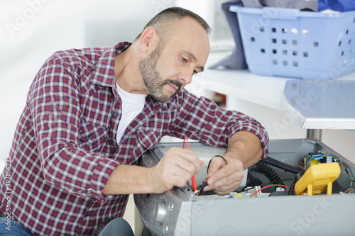 male technician inspecting and fixing a washer and dryer
