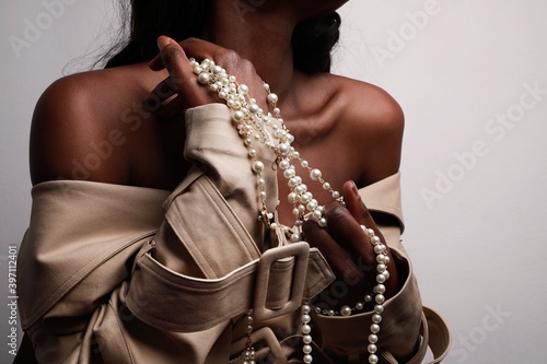 Afro American woman wearing beige trench and posing for camera in studio.