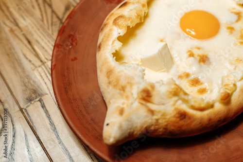 Top view on traditional Adjarian Khachapuri - open baked pie with melted salt cheese suluguni and egg yolk on wooden tray. Traditional georgian food