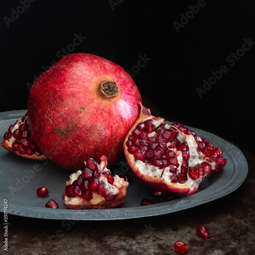 Still life with pomegranate on a platter, square photo