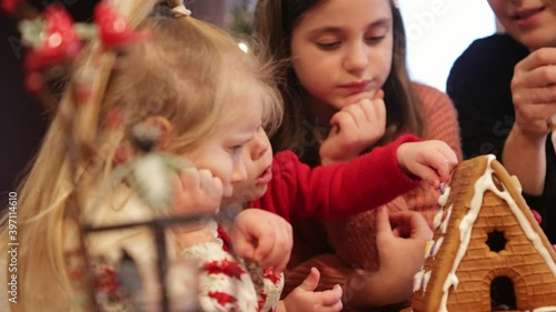 Happy Family, During Christmas Time Decorating Gingerbread House, Stay Home activity, December 2020, 3 Cute sisters cover cookies with Frosting and Sugar, Best Family Traditions 