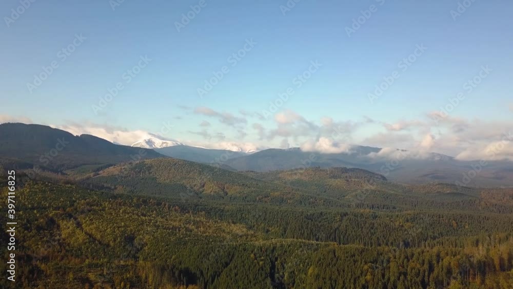 Aerial view of majestic mountains covered with green spruce forest and high snowy peaks.
Aerial view of majestic mountains covered with green spruce forest and high snowy peaks.