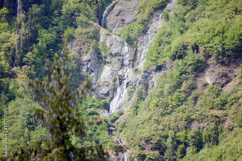 Mountain waterfalls on the green slope of a high mountain