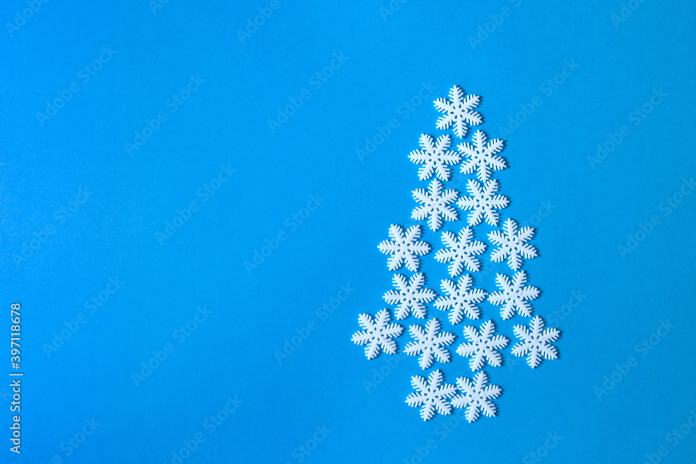 Christmas tree made of snowflakes on a blue background with space for text. Top view, flat lay, overhead, copy space. Creative composition. Christmas tree made of snowflakes on a blue background with space for text. Top view, flat lay, overhead, copy space. Creative composition.