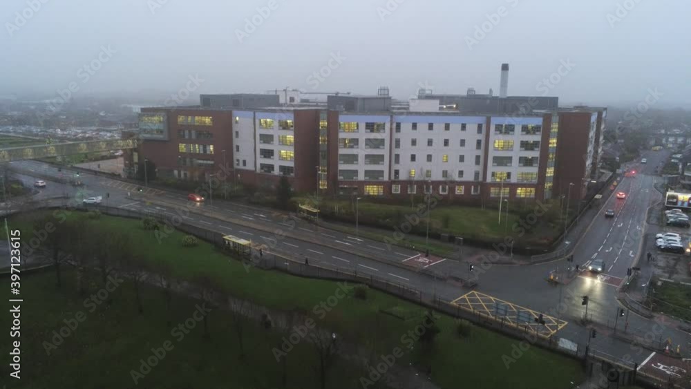 Misty foggy hospital building UK town traffic aerial view pull away slow descend