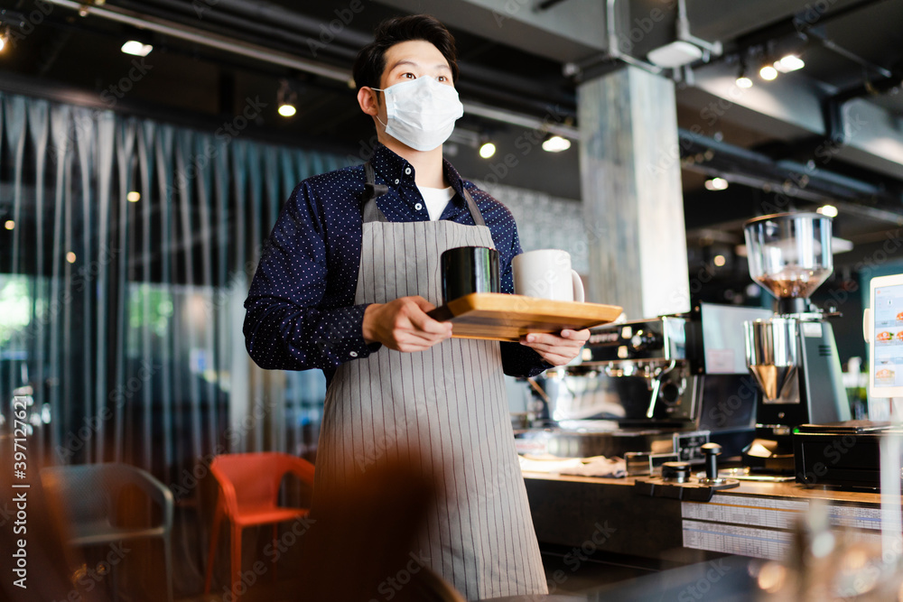 Asian barista man wearing mask serving coffee in cafe. Asian barista man wearing mask serving coffee in cafe.