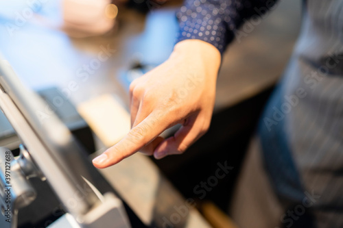 Hand of barista selecting food from digital menu in tablet.