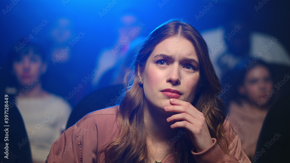 Upset young woman worrying in cinema. Closeup sad girl watching sentimental film