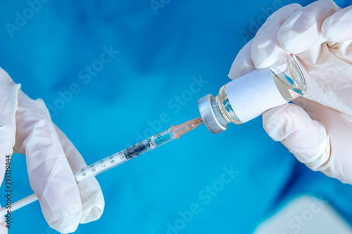 A health worker holding a syringe and a vial vaccine, getting it fill with medicine.