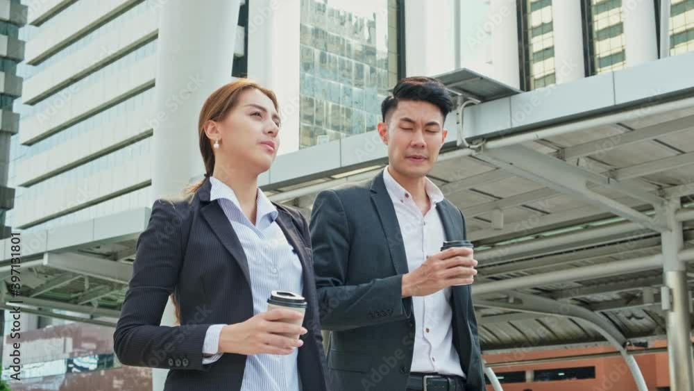 Asian young business couple walking in the city, holding a coffee cup. Asian young business couple walking in the city, holding a coffee cup.
