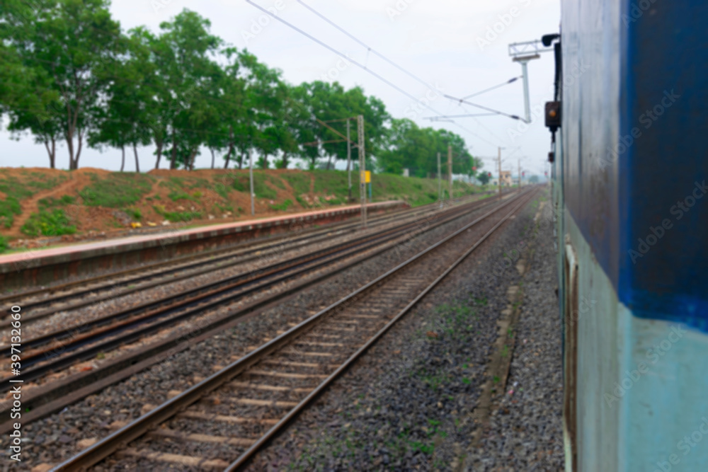 Obraz premium Blurred image of Indian rail lines with green trees in the side.