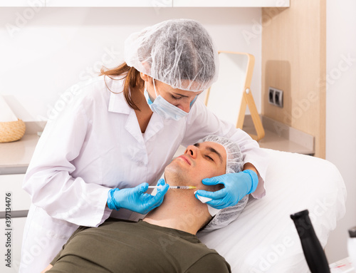 Young man caring of his skin  getting injection for face skin tightening at aesthetic clinic
