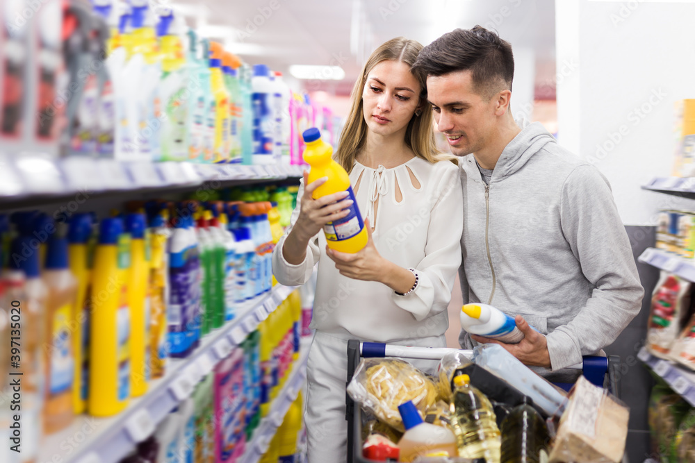 Positive couple doing shopping together, choosing household detergents in store