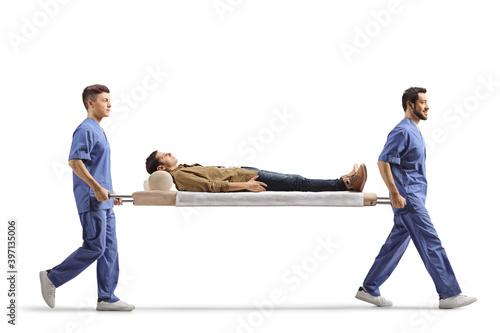 Male health workers carrying young male patient on a stretcher