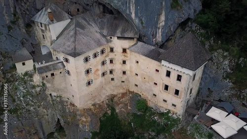 Aerial tilt up, Predjama castle built in a mountain, Slovenian iconic landmark
 photo