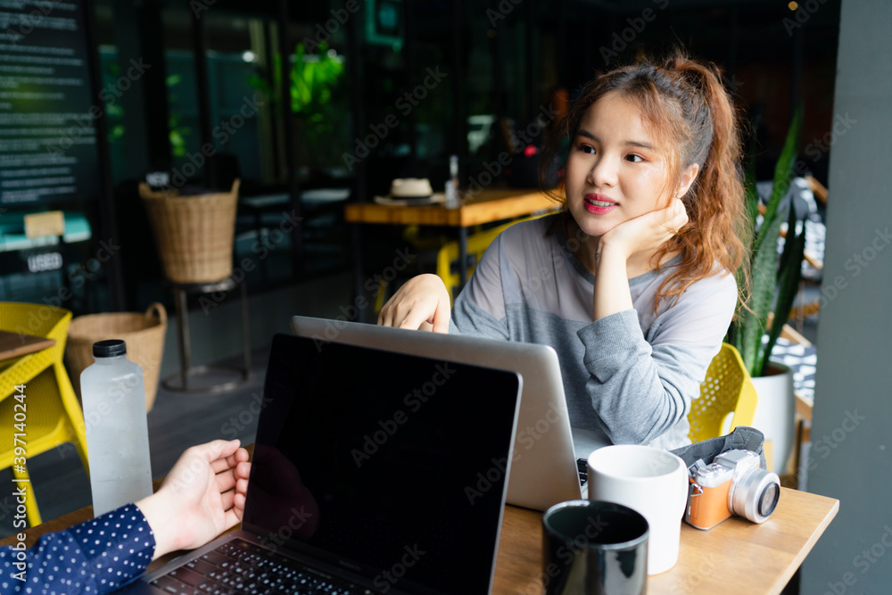 Woman working on laptop with partner at cafe outdoors. Woman working on laptop with partner at cafe outdoors.