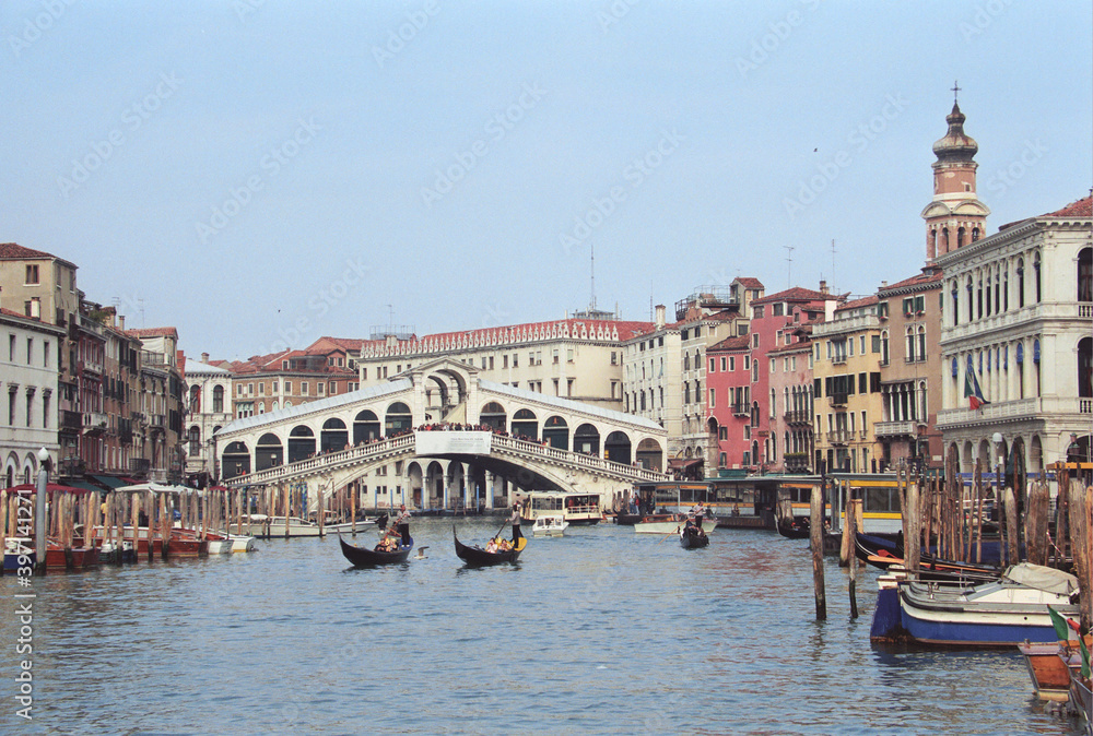 View of Venetian gondola boats and world famous Rialto Bridge spanning the Grand Canal in Venice, Italy.