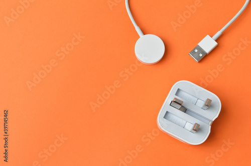 Smartwatch magnetic charging cable isolated on a orange background. Modern technology.