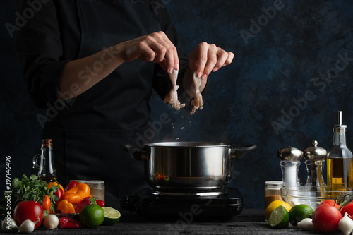 Macro shot of chef cooking asian dish and puts octopuses into pan with boiling water. Backstage of preparing seafood on dark blue background. Concept of exotic asian cuisine. Frozen motion.