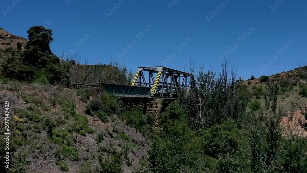 Railway bridge approach from low angle , rising up with drone to reveal steel construction in rural countryside