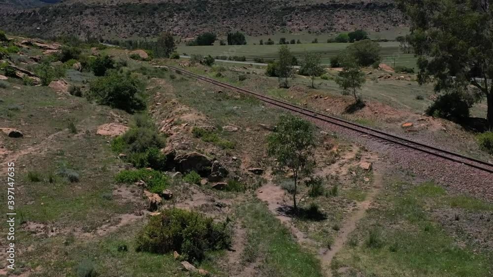 Railway track in rural countryside pulling up with drone to reveal surrounding area and road Railway track in rural countryside pulling up with drone to reveal surrounding area and road