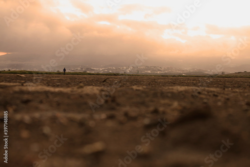Panoramic view of a man walking in a brown cracked ground