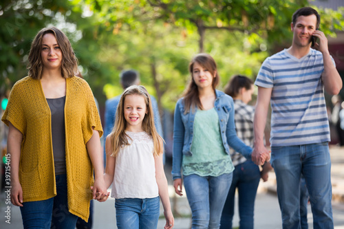 Young mom with little glad daughter walking in the park