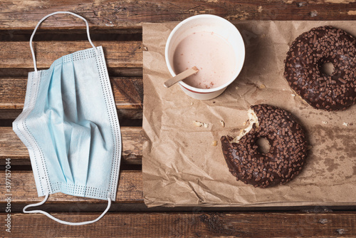 Fotografie Eating take-out food during pandemic: donuts, milked cocoa in a disposable cup beside a protective mask